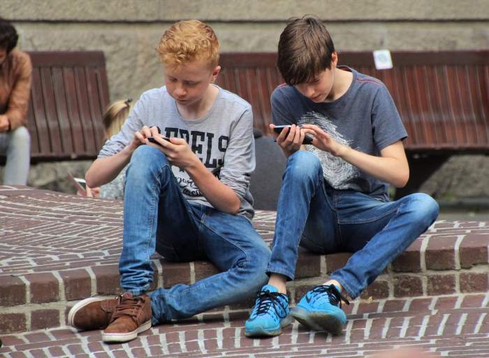 foto twee jongens bezig met hun smartphone